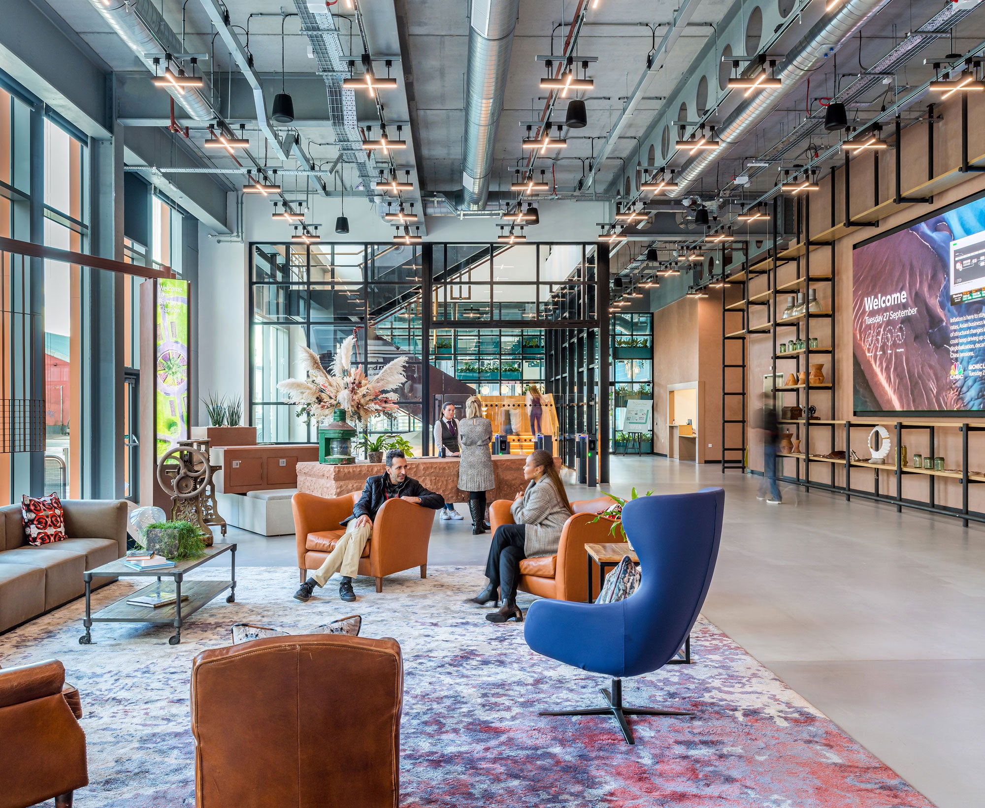 Barclays Glasgow reception entrance area with colourful chairs and people talking to each other seated and standing
