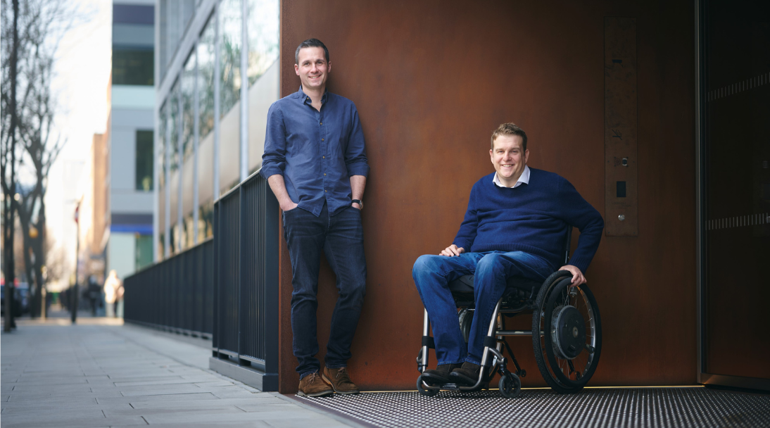 About us - Motionspot co-founders, Ed Warner standing next to James Taylor in his wheelchair, outside a building