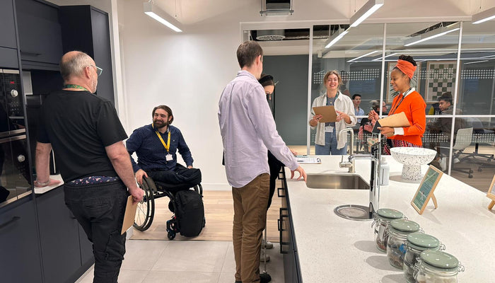 6 people around a kitchenette area in a workplace discussing its design in a Motionspot user engagement session