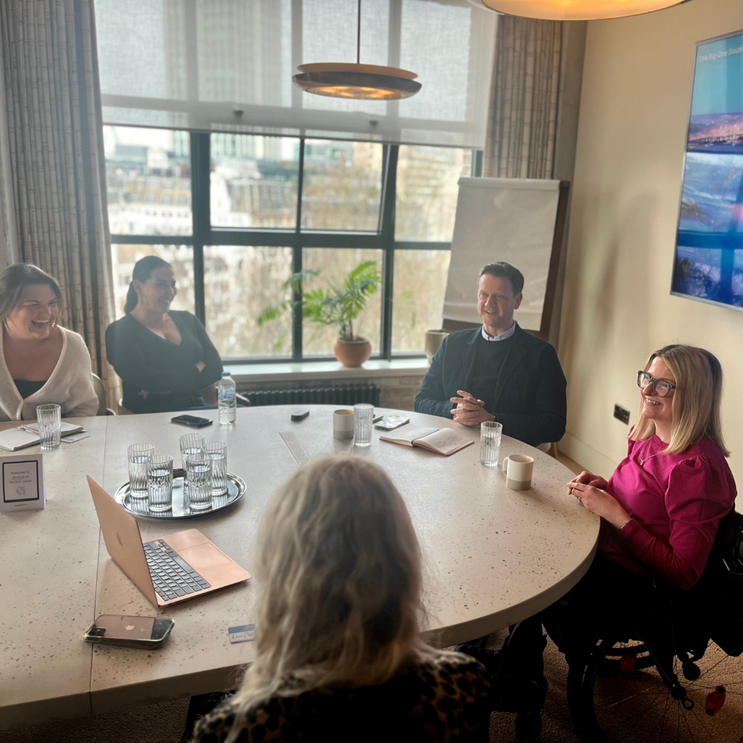 A group of 5 professionals sitting around a table in discussion