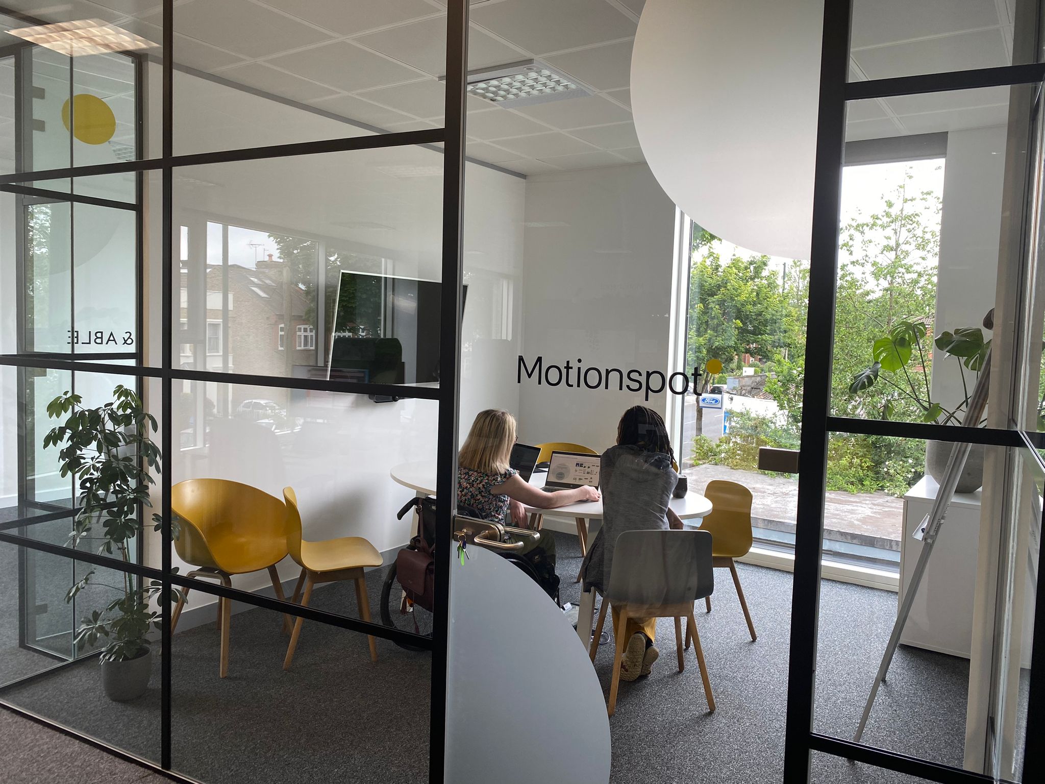 two members of the motuonspot team in the motionspot design studio filled with large windows and light and planting working together iat a table 