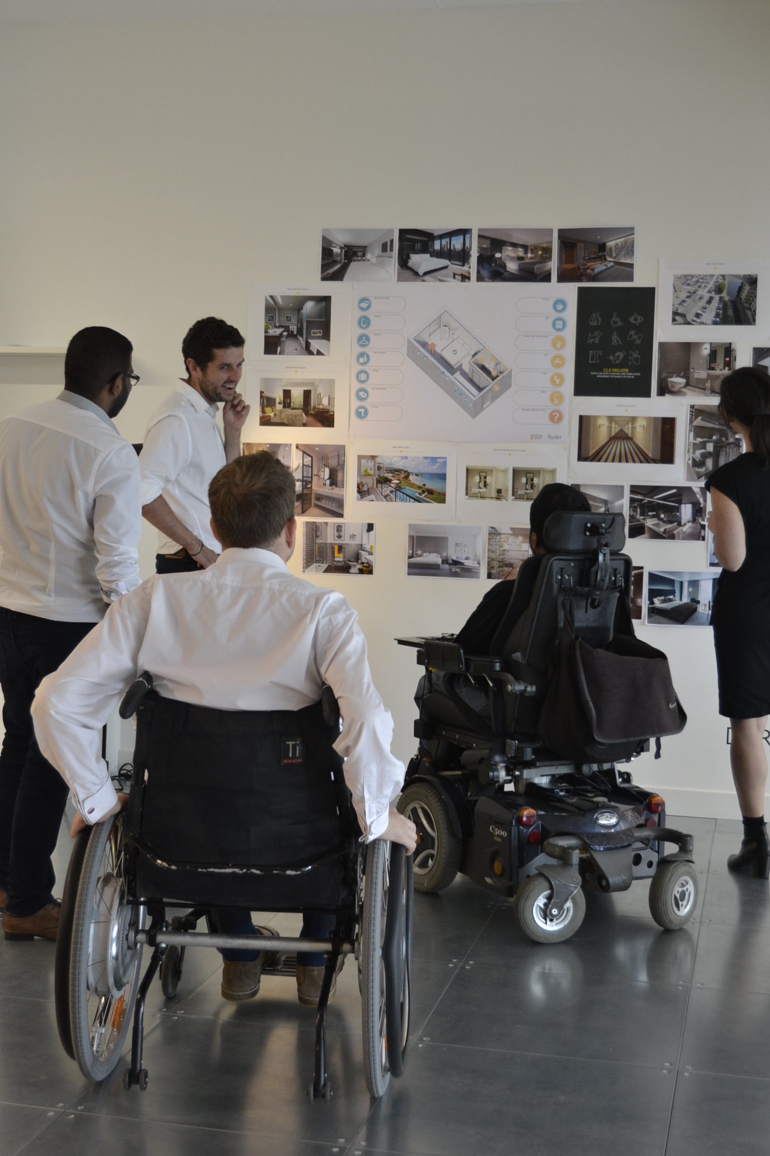 user group including wheelchair users discussing designs on a wall
