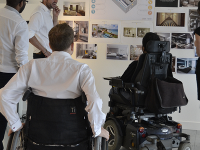 user group including wheelchair users discussing designs on a wall